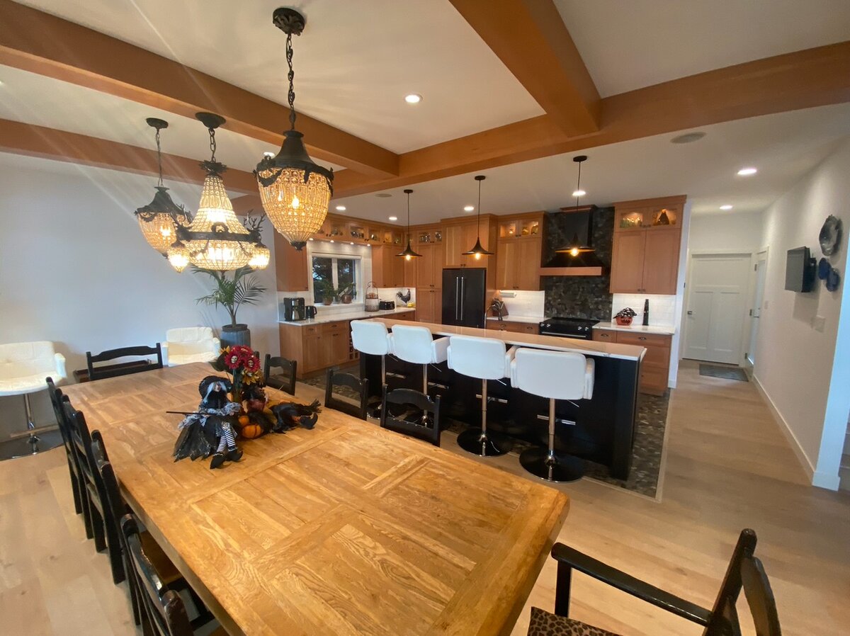 custom home kitchen design with wood ceiling beams, pendant lighting and custom cabinetry