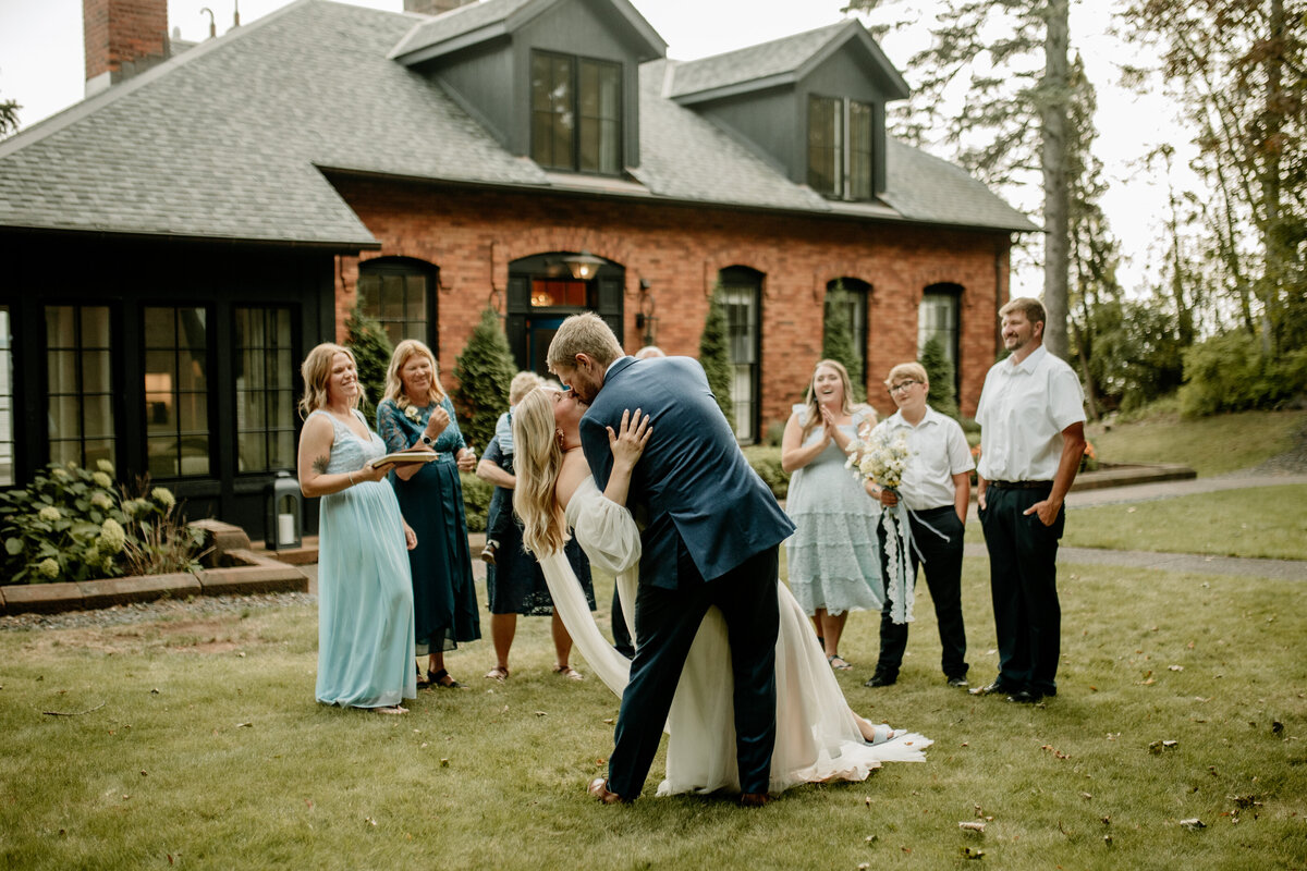 Bride and groom share their first kiss as their loved ones cheer them on during an intimate wedding ceremony.