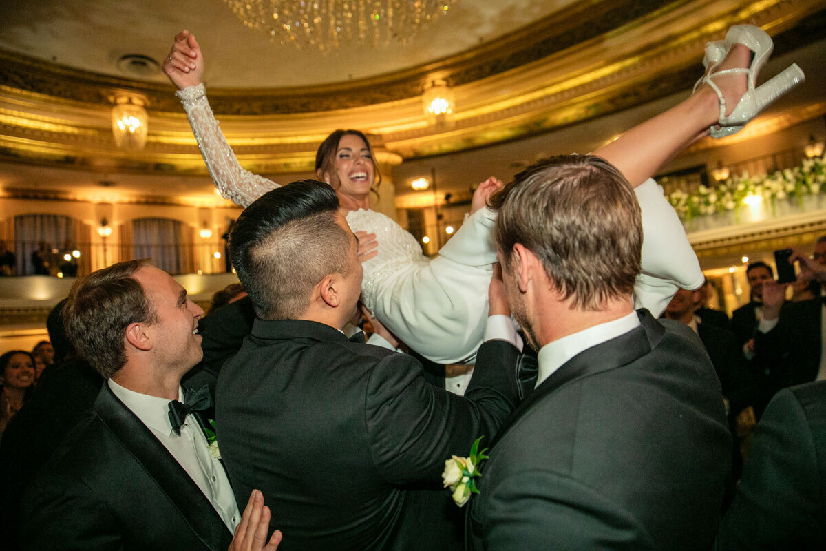 A bride is being lifted in the air by a group of men