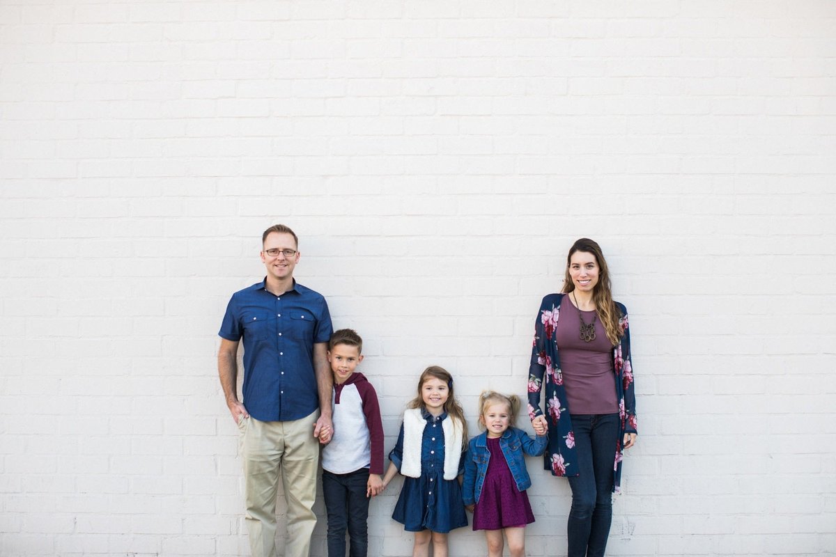 Family of five pose for family photos in front of a white wall in Fullerton, CA
