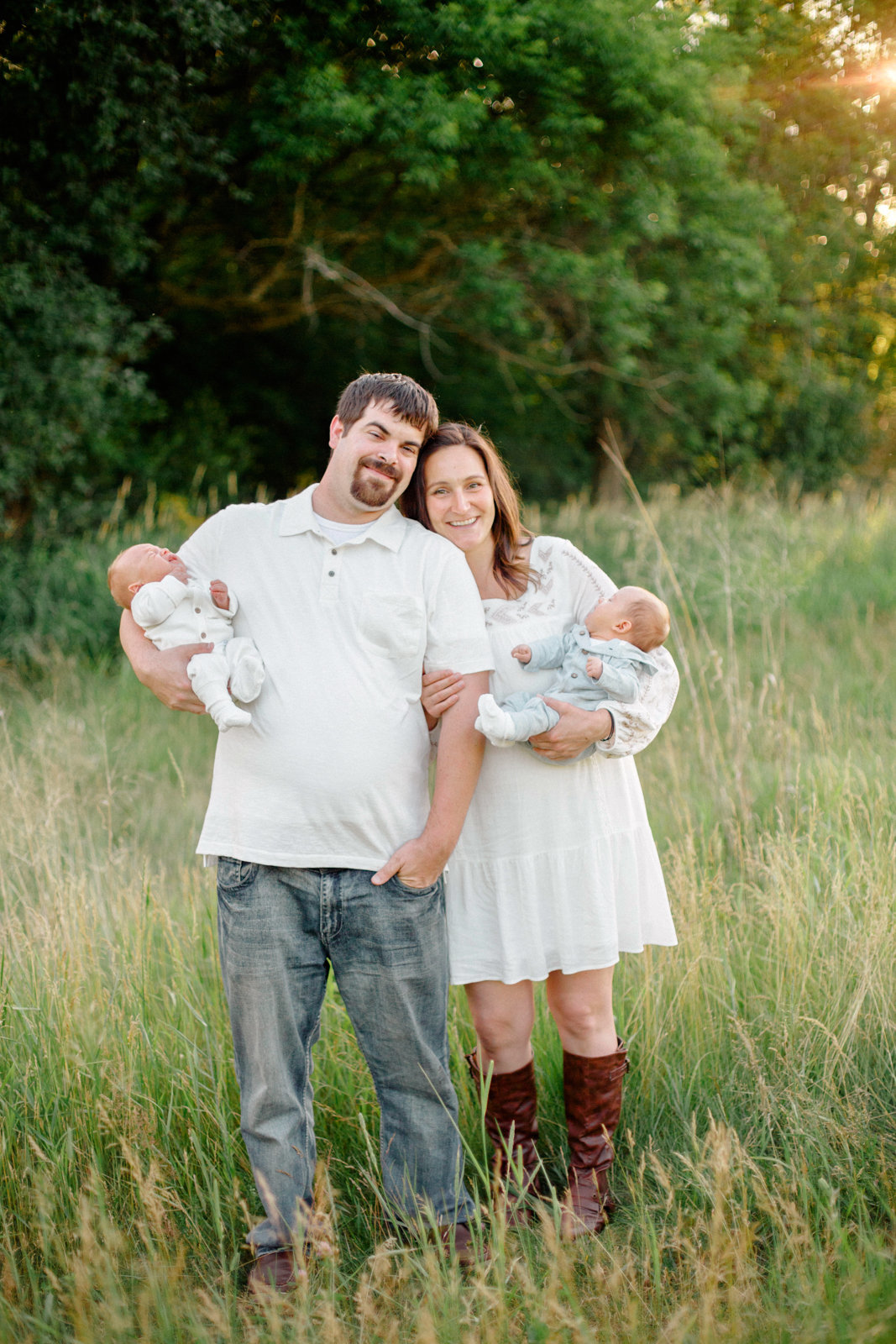 parents hold twin boys out in summer fields and forrests for newborn photography rochester minnesota