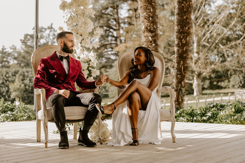 Mariés se regardant, assis dans un fauteuil chacun en extérieur pendant la cérémonie laïque, sous l'appareil de Laura, photographe mariage en Vendée.