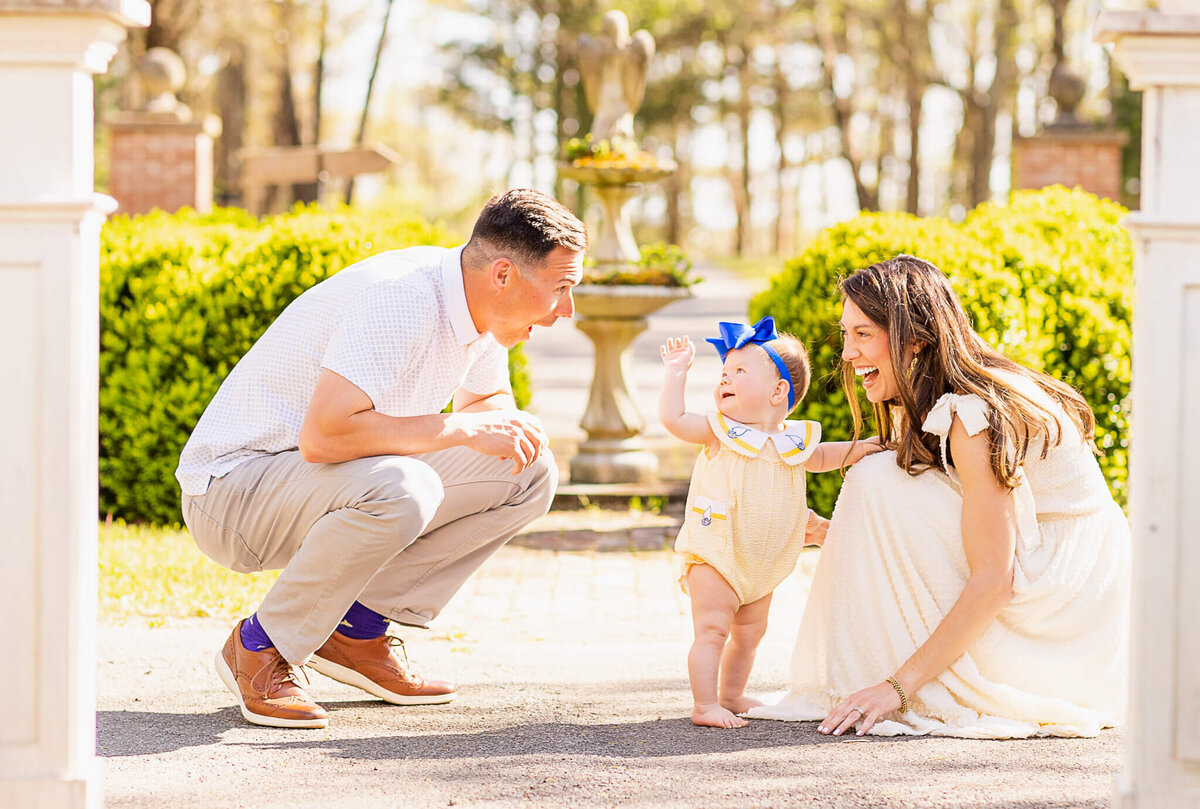 Family of three with a little girl in a yellow romper and blue bow