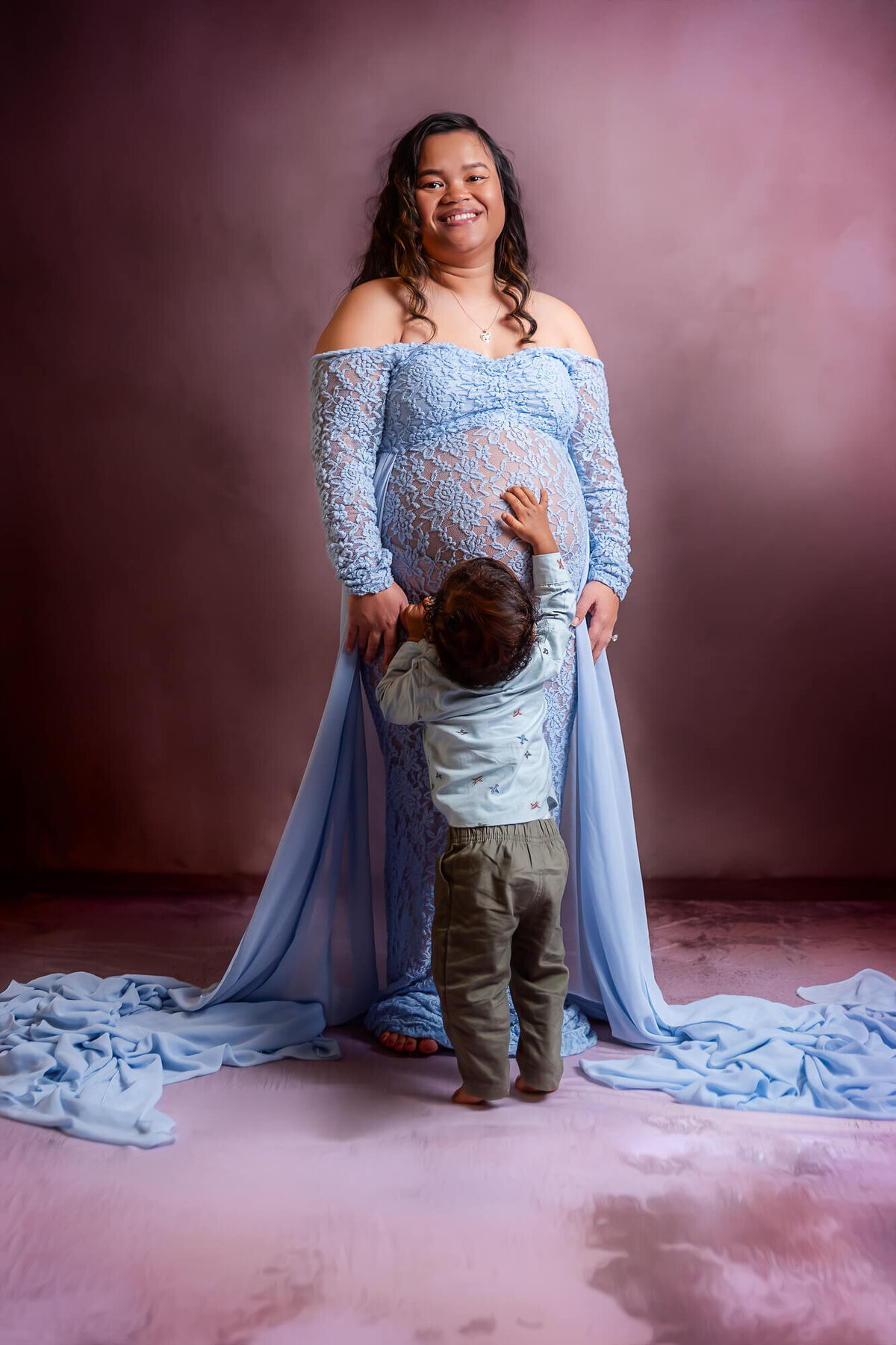 A pregnant woman in a blue dress lovingly cradles her baby, showcasing a beautiful moment of motherhood.
