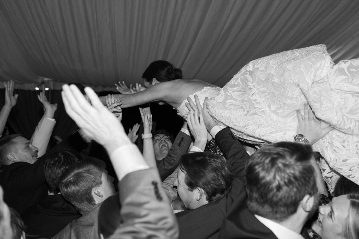 Black and white photo of the bride crowd-surfing during the wedding reception at SpringHouse in Lake Martin, Alabama.
