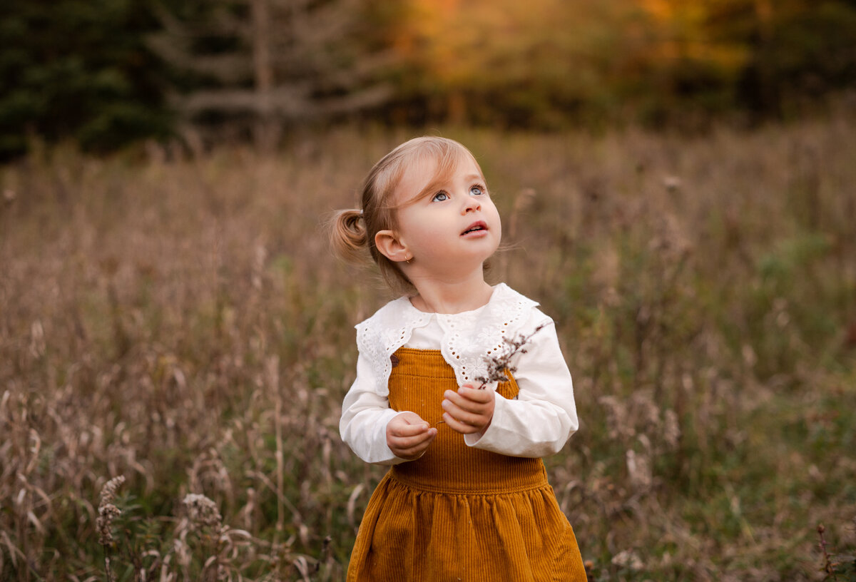 Young girl wearing a Zara dress looking up in a field in Ottawa