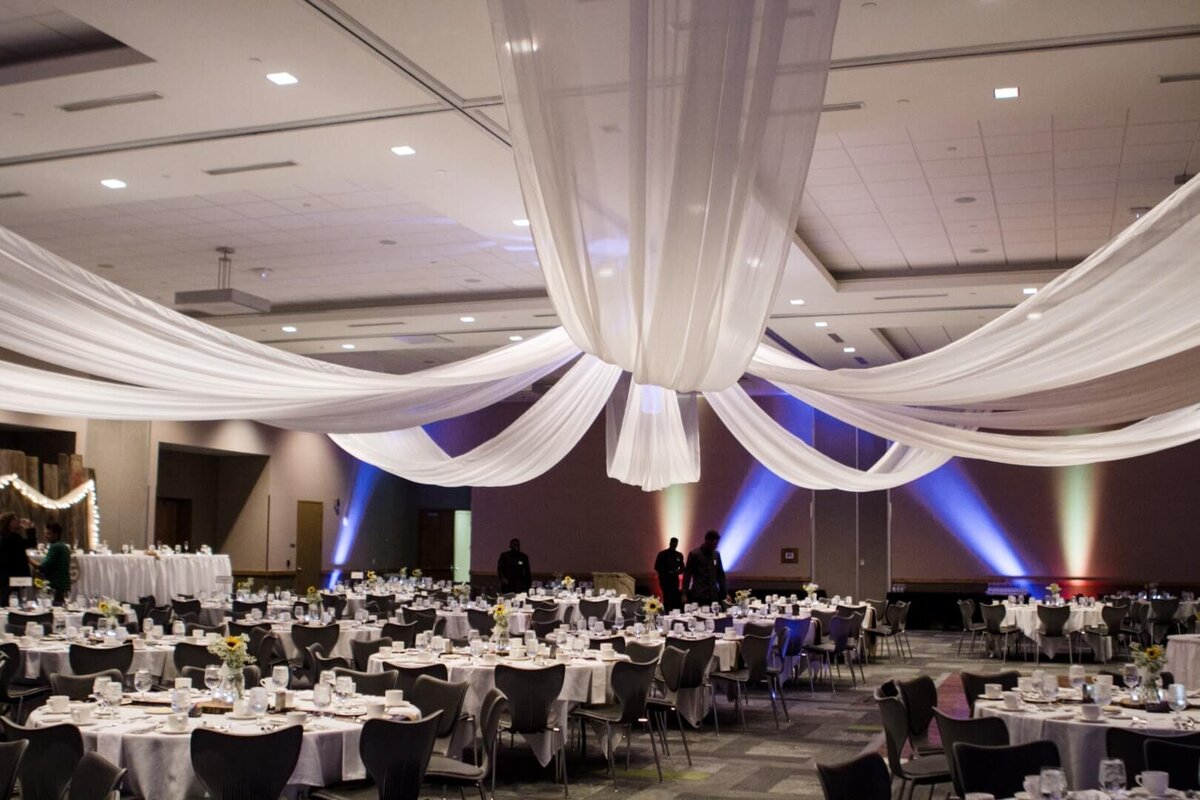 White linens designed ceiling, tables and chairs set-up.