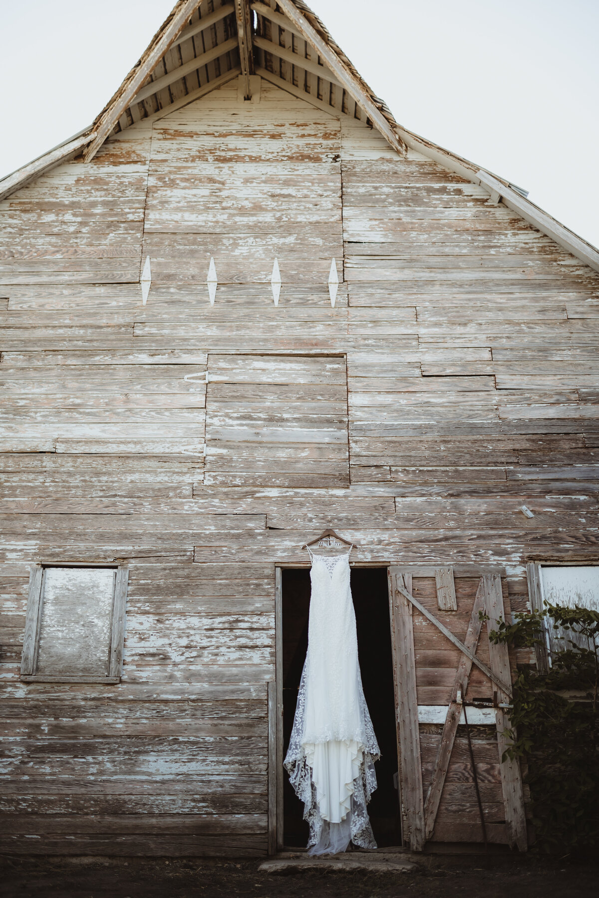 WEDDING GOWN HANGING IN BARN DOORWAY IN KANSAS