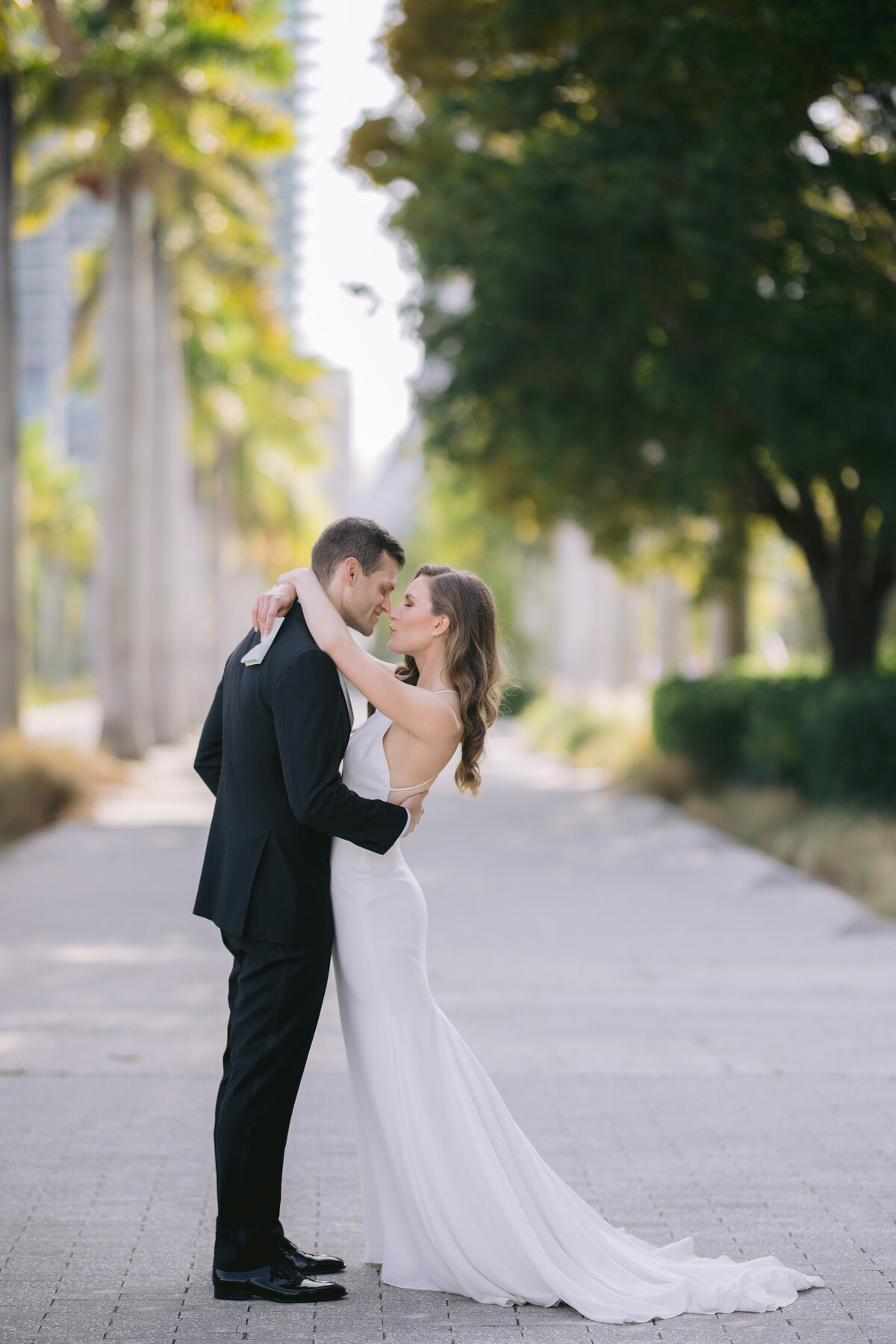 Bride and groom sharing an intimate moment among palm trees in Miami, Florida.
