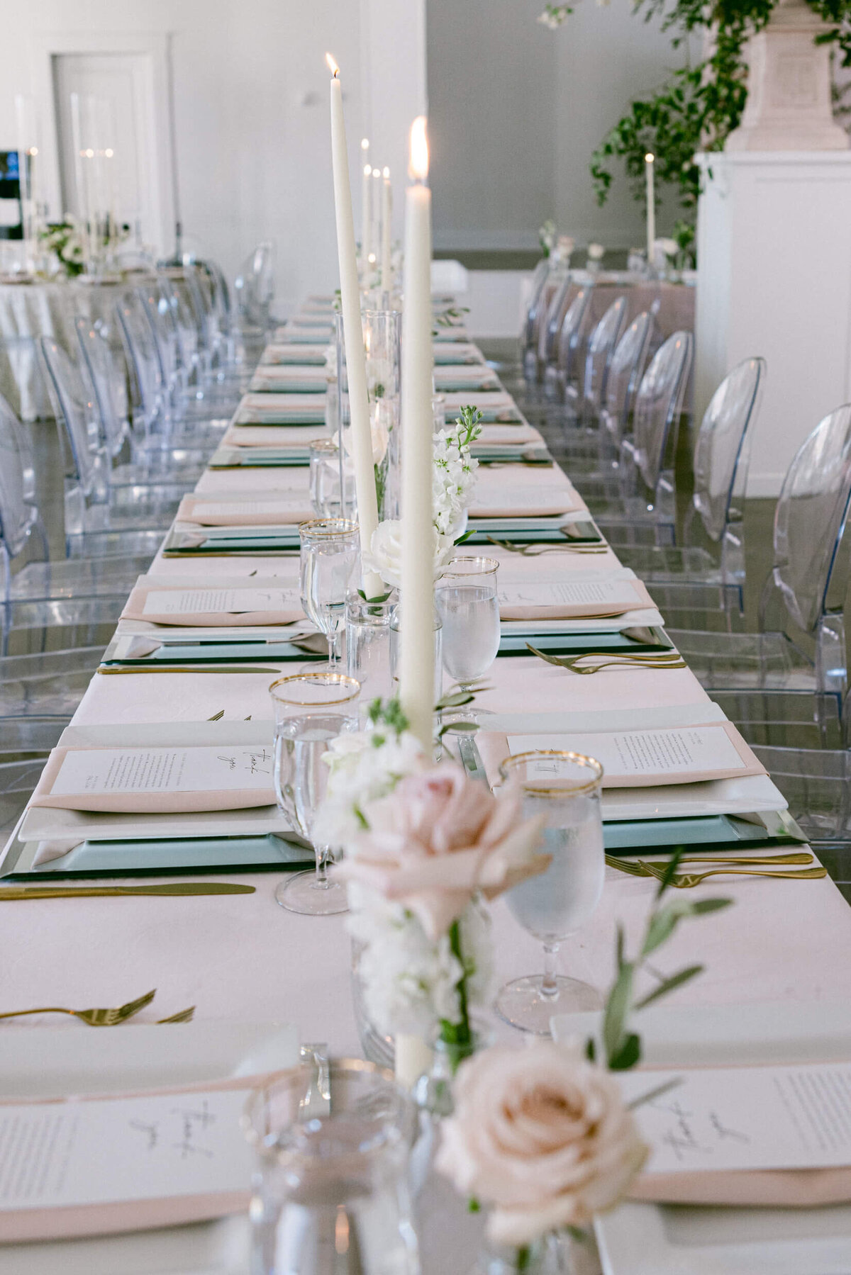 A wedding photo of the dinner table covered in linens and candles