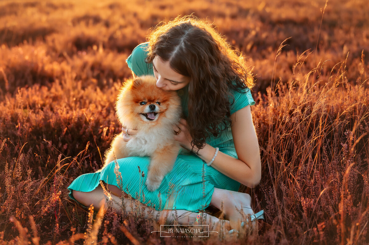 Nienke met haar pomeriaan hondje Buddy op haar schoot en geeft hem een kusje op zijn voorhoofd