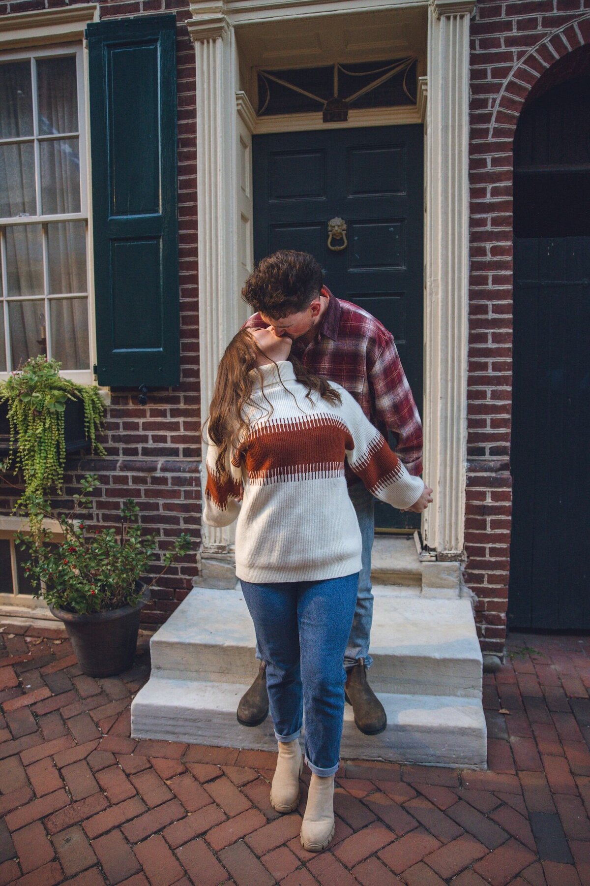 Couple cuddling by colorful Philly rowhouses.