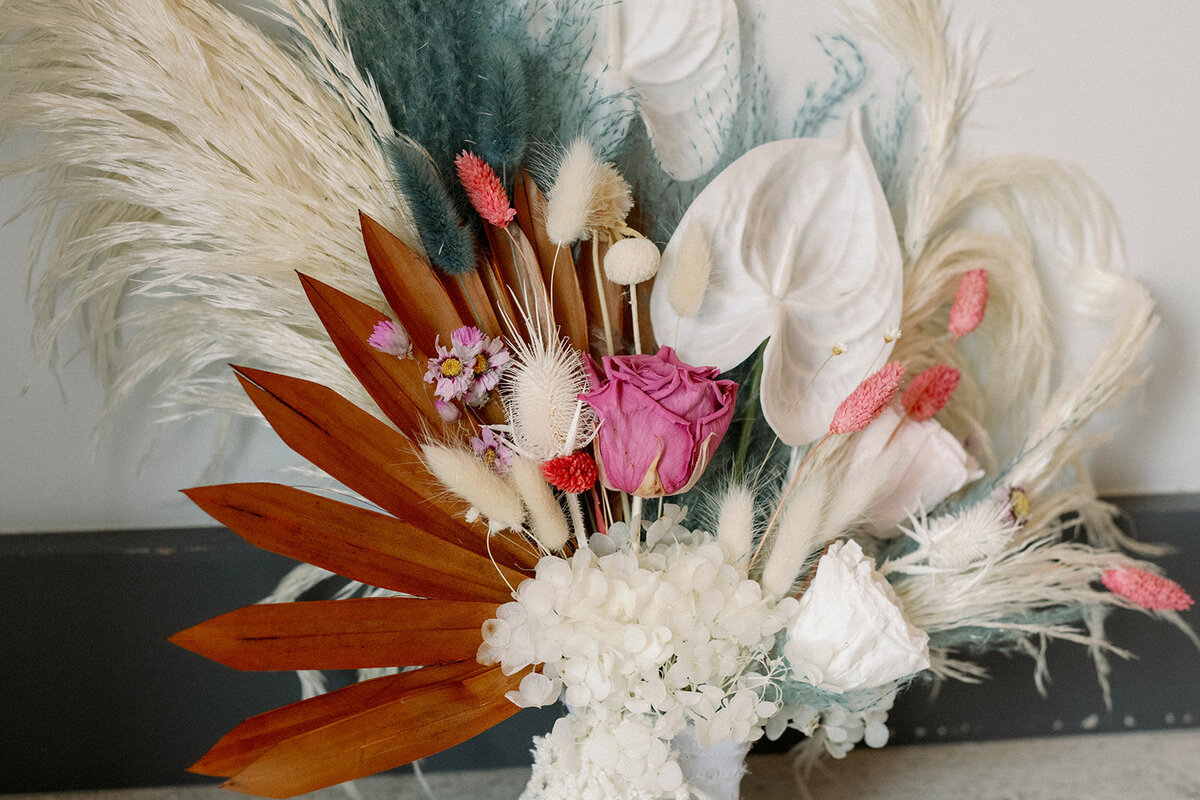 Dried floral bouquet with white, brown, pink, and teal accents.