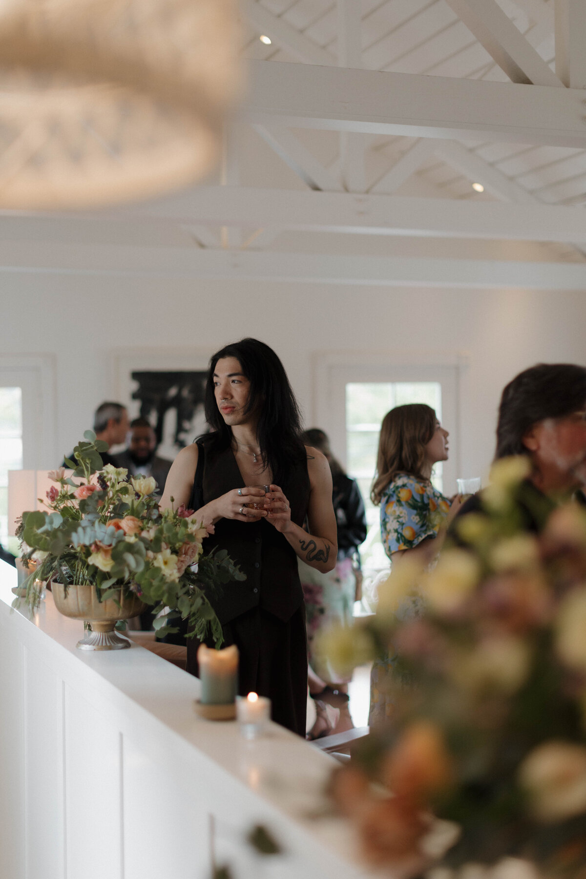 A stylish wedding guest enjoying a cocktail during a modern reception. We specialize in documentary-style wedding photography that captures effortless, candid moments, elegant details, and the refined ambiance of a luxury wedding celebration.