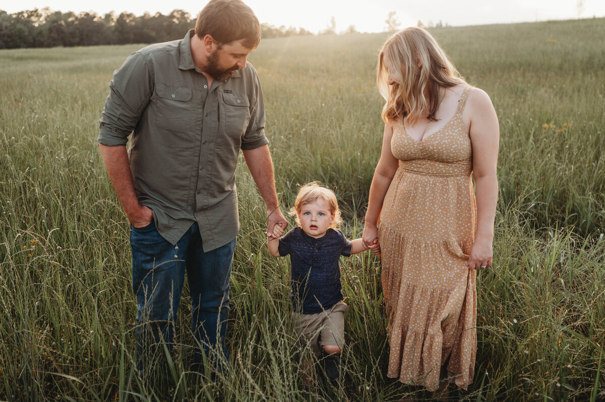 Mother and Father hold hands with their little boy while walking through