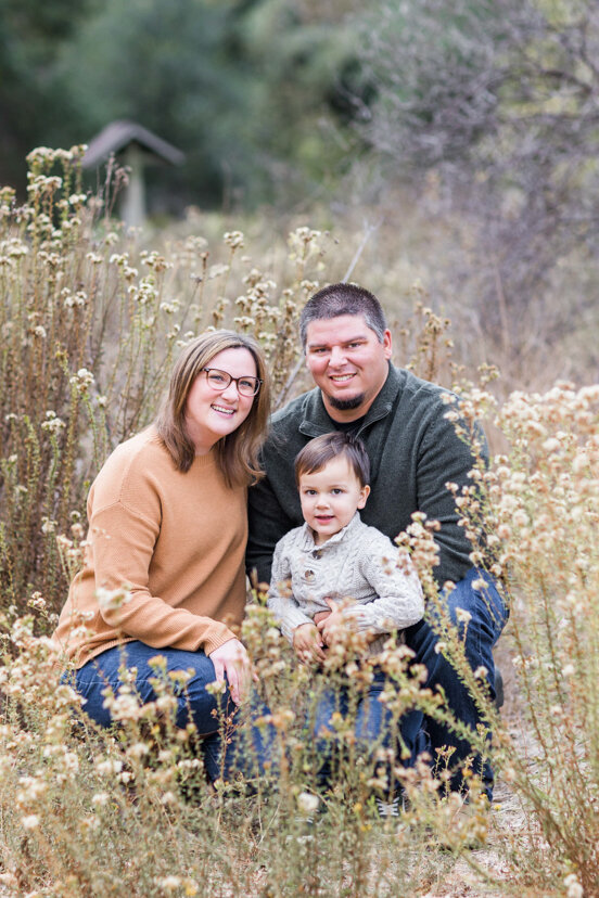 family-with-young-son-sitting-in-golden-field--sweetwater-river-bridge-san-diego