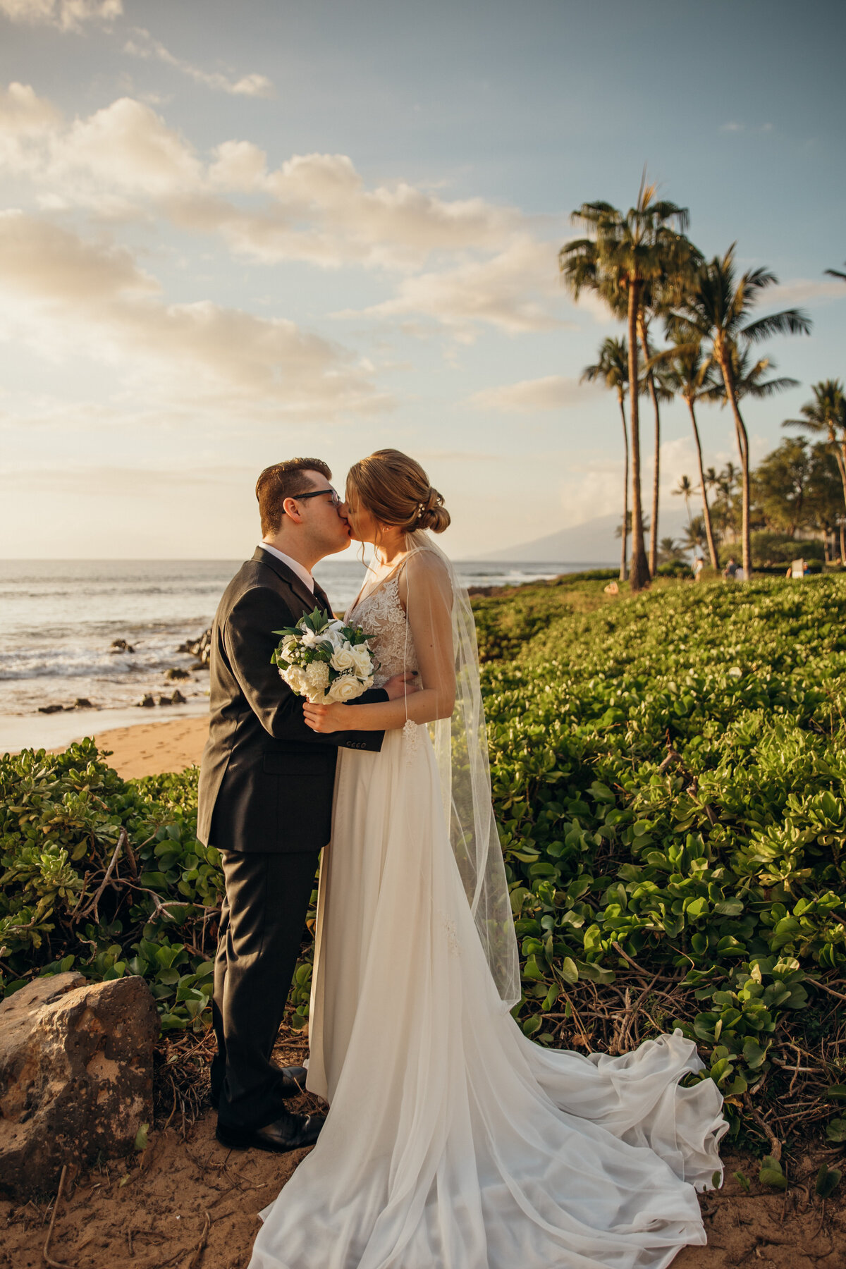 Maui Wedding Photographer captures groom kissing bride after Maui beach wedding