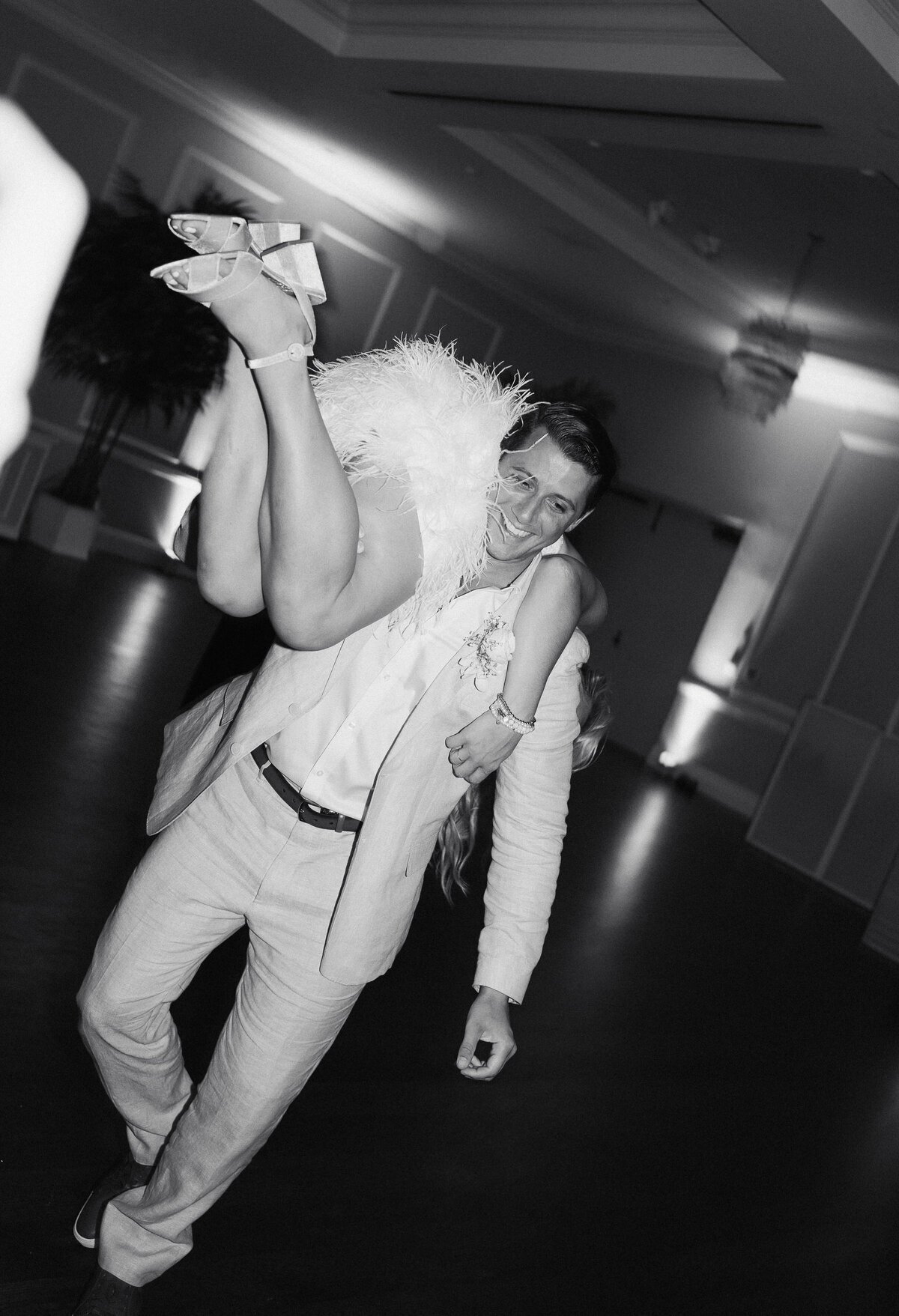 Groom carrying bride on shoulder taken by wedding film photography professional