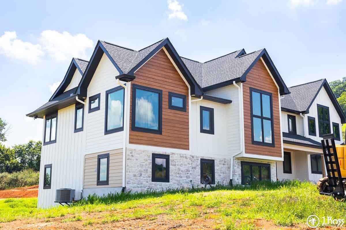Modern farmhouse under construction featuring home outside painting, Kingsport, Tennessee—white vertical siding, dark roof, and black-framed windows.
