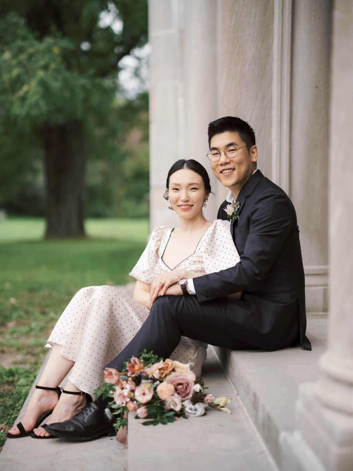 The engaged couple are happily seated in the entrance staircase of Coe Hall at Planting Fields Arboretum, NY