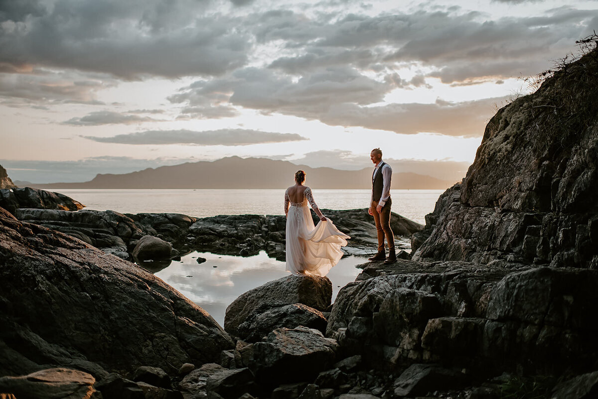 Couple watching the sun set on the rocks during their elopement.
