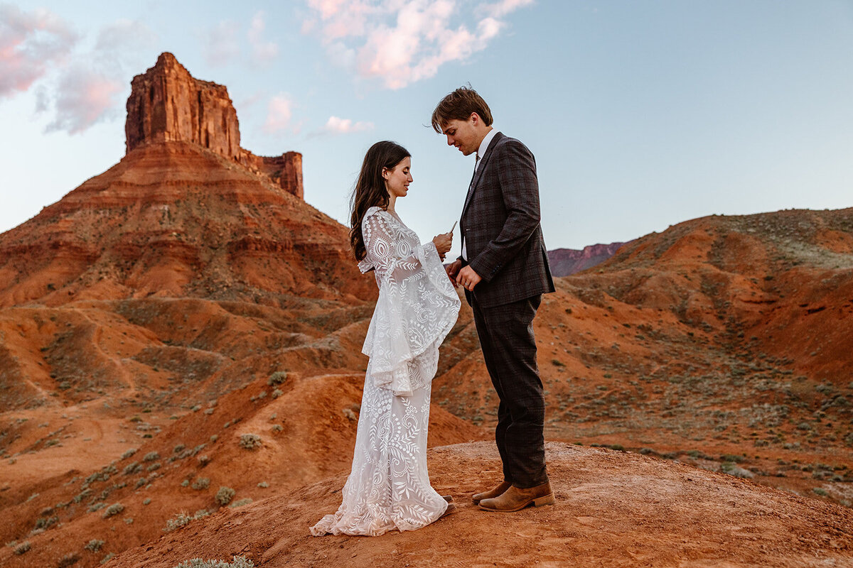 A couple exchanges vows in front of red rocks during their elopement in Moab