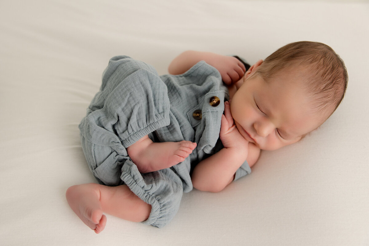 baby boy in blue overall in white studio