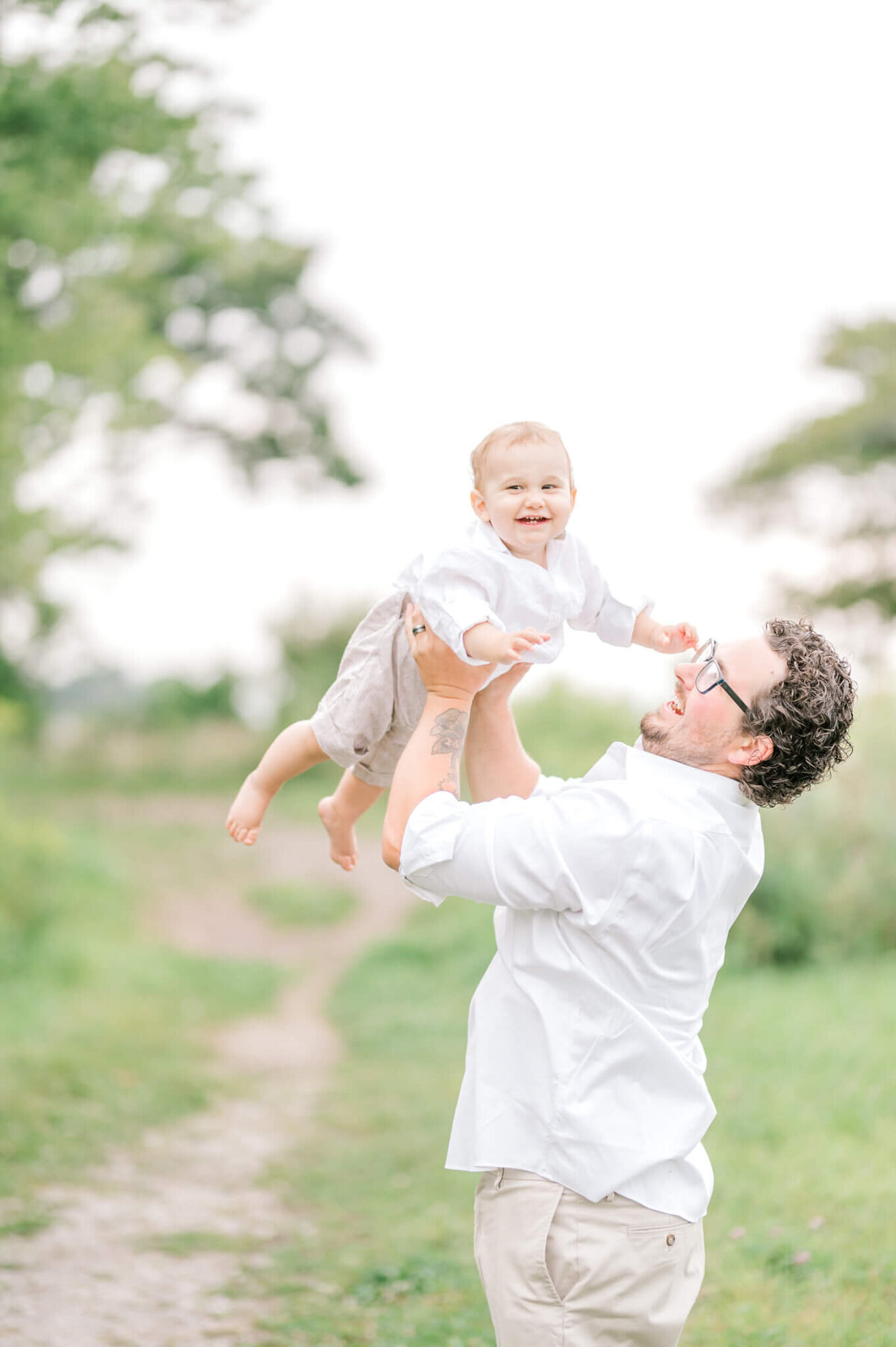 Dad throwing baby son in the air as he is smiling and laughing