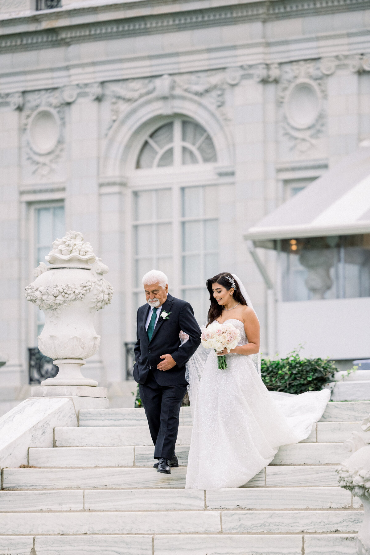 bride escorted down the isle by her father walking down the back stairs torwards oceanside lawn ceremony at rosecliff mansion in newport rhode island
