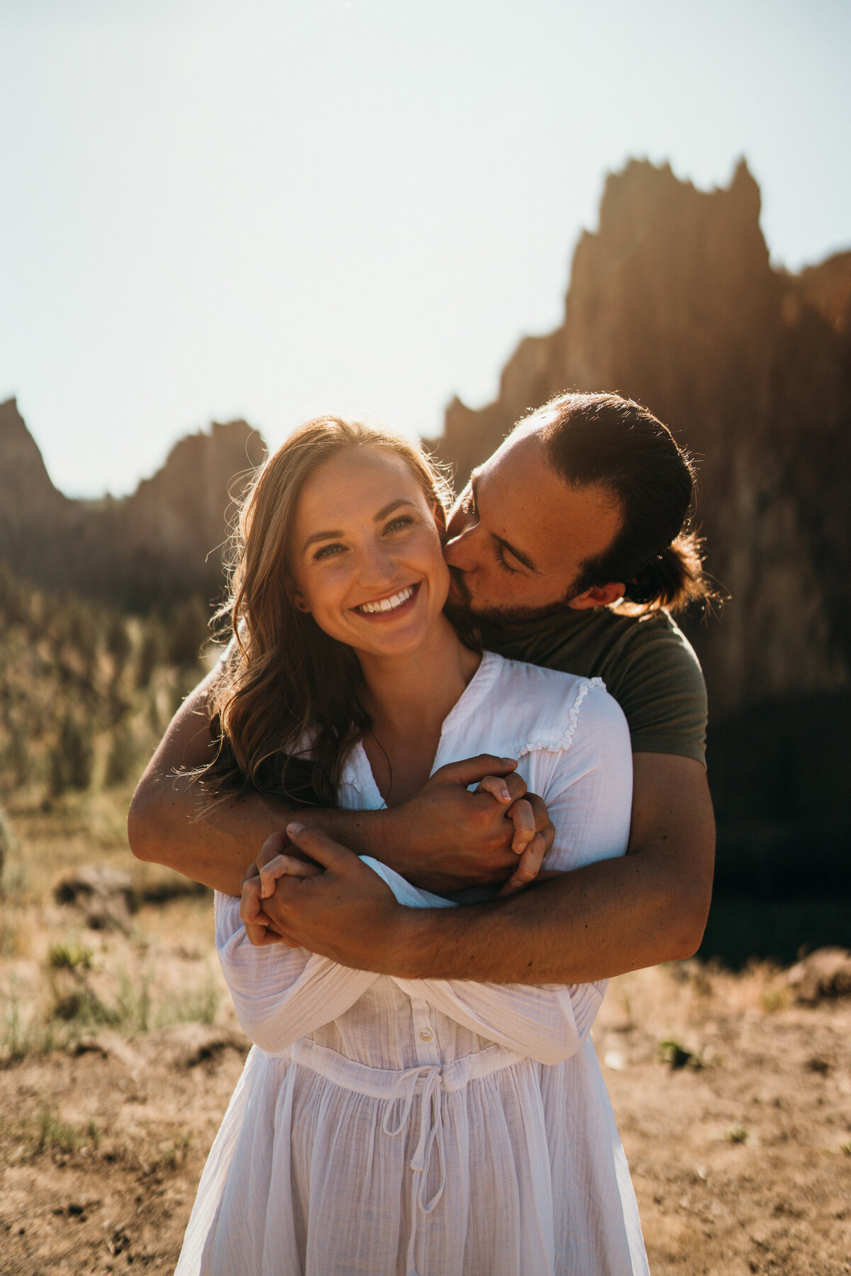 couple embracing, kisses on the cheek, at sunset, in oregon
