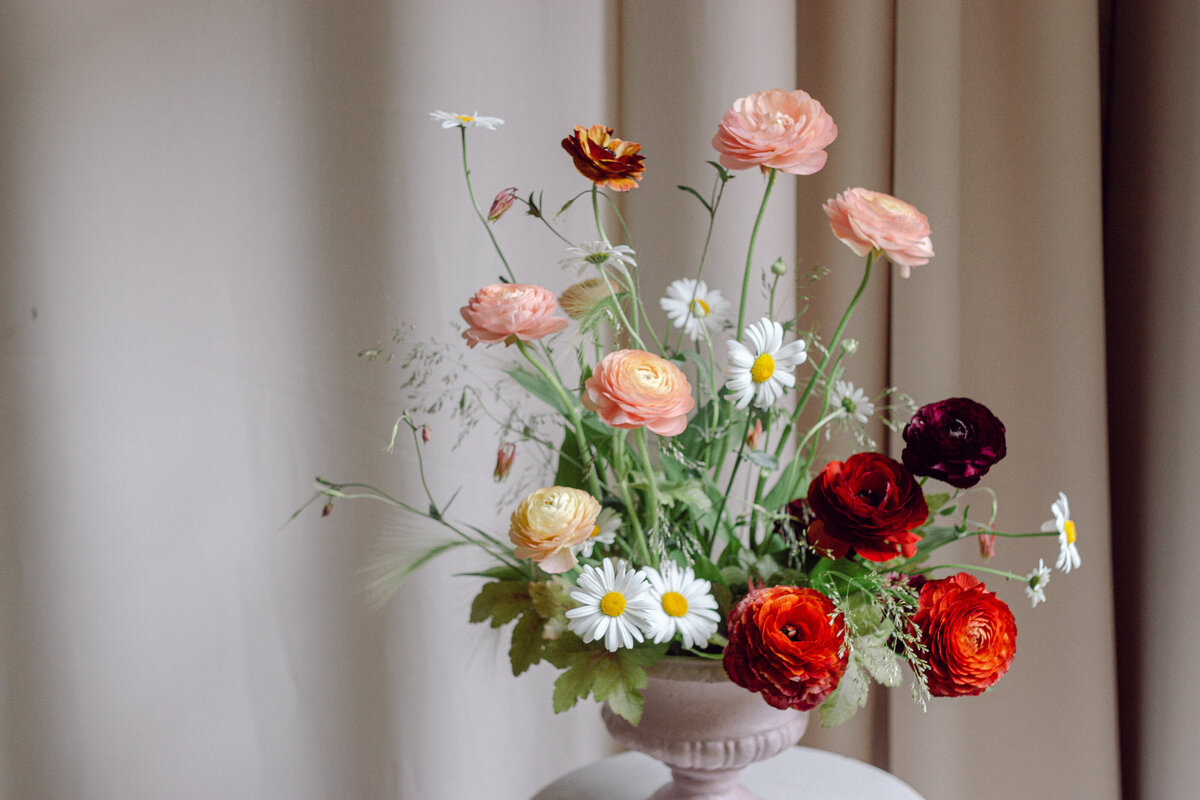 Bright daisies and ranunculus in a floral arrangement at a Montreal wedding.