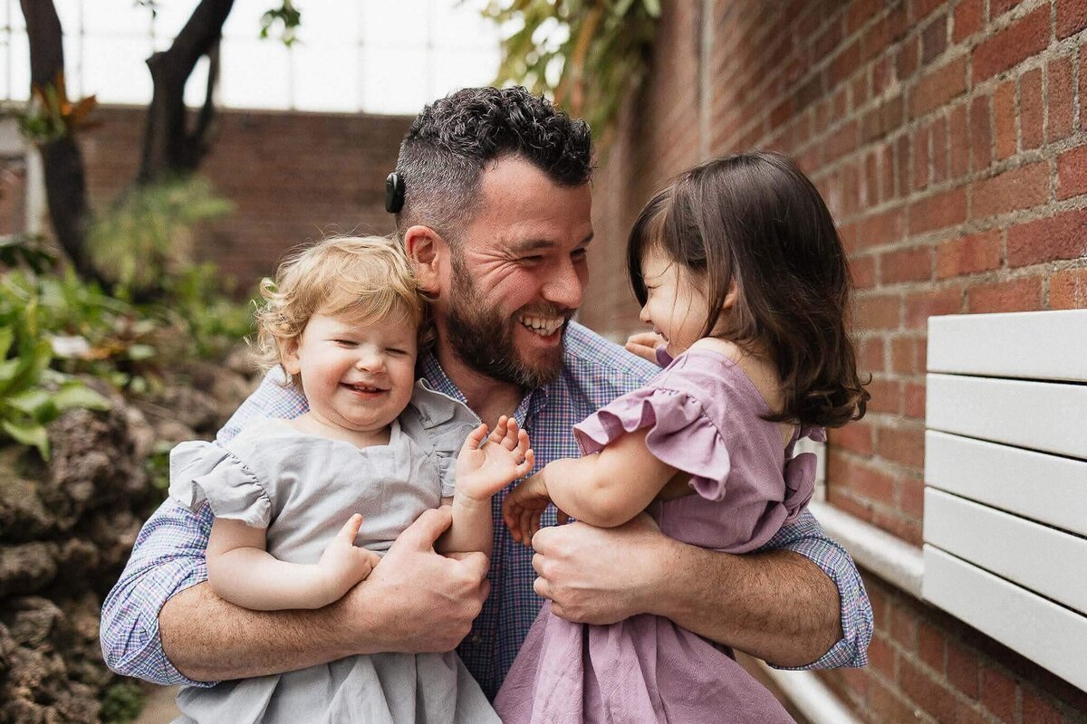 Dad hugging two daughters at Rockefeller Greenhouse family photography session.