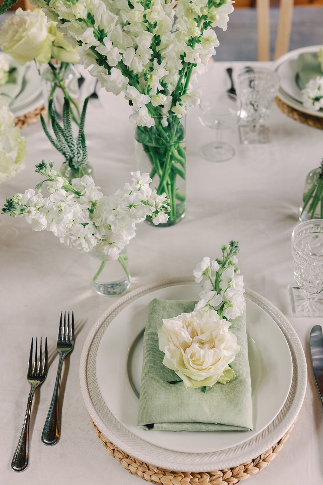 PLace setting with white plates, green napkins, and white and green florals