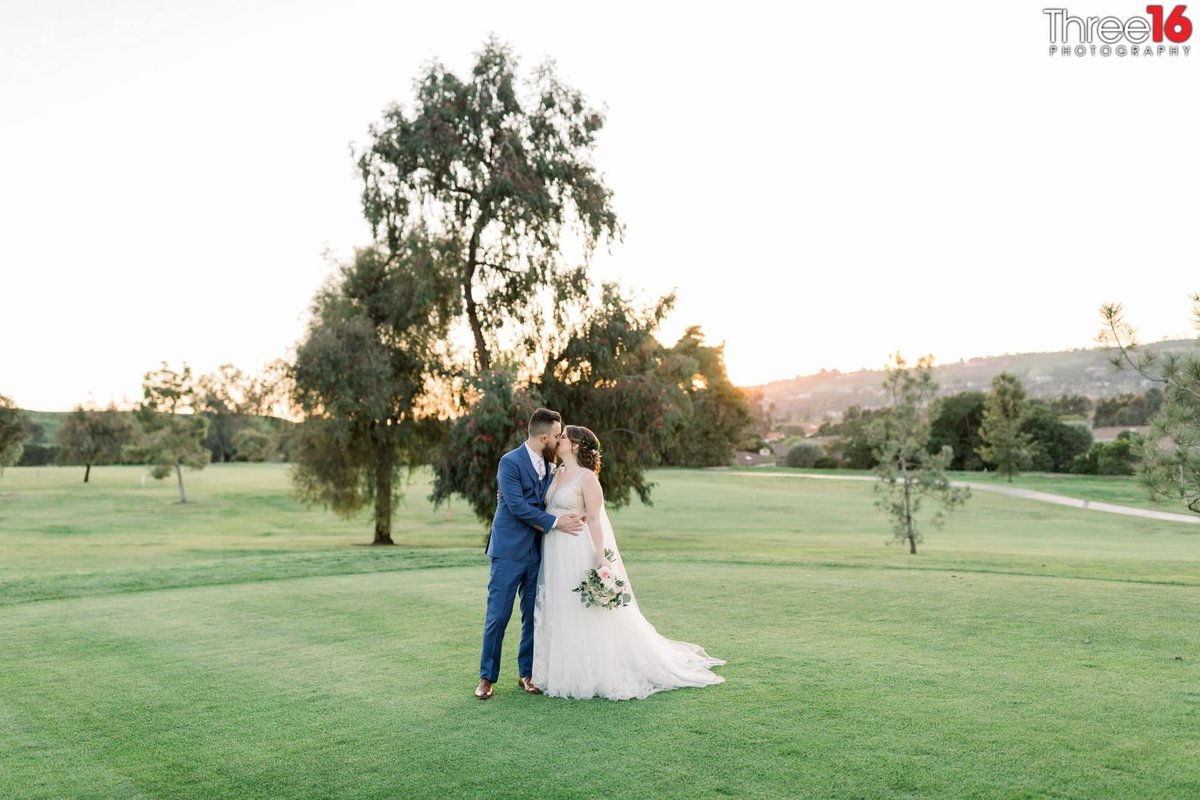 Bride and Groom stop for a kiss on the putting green