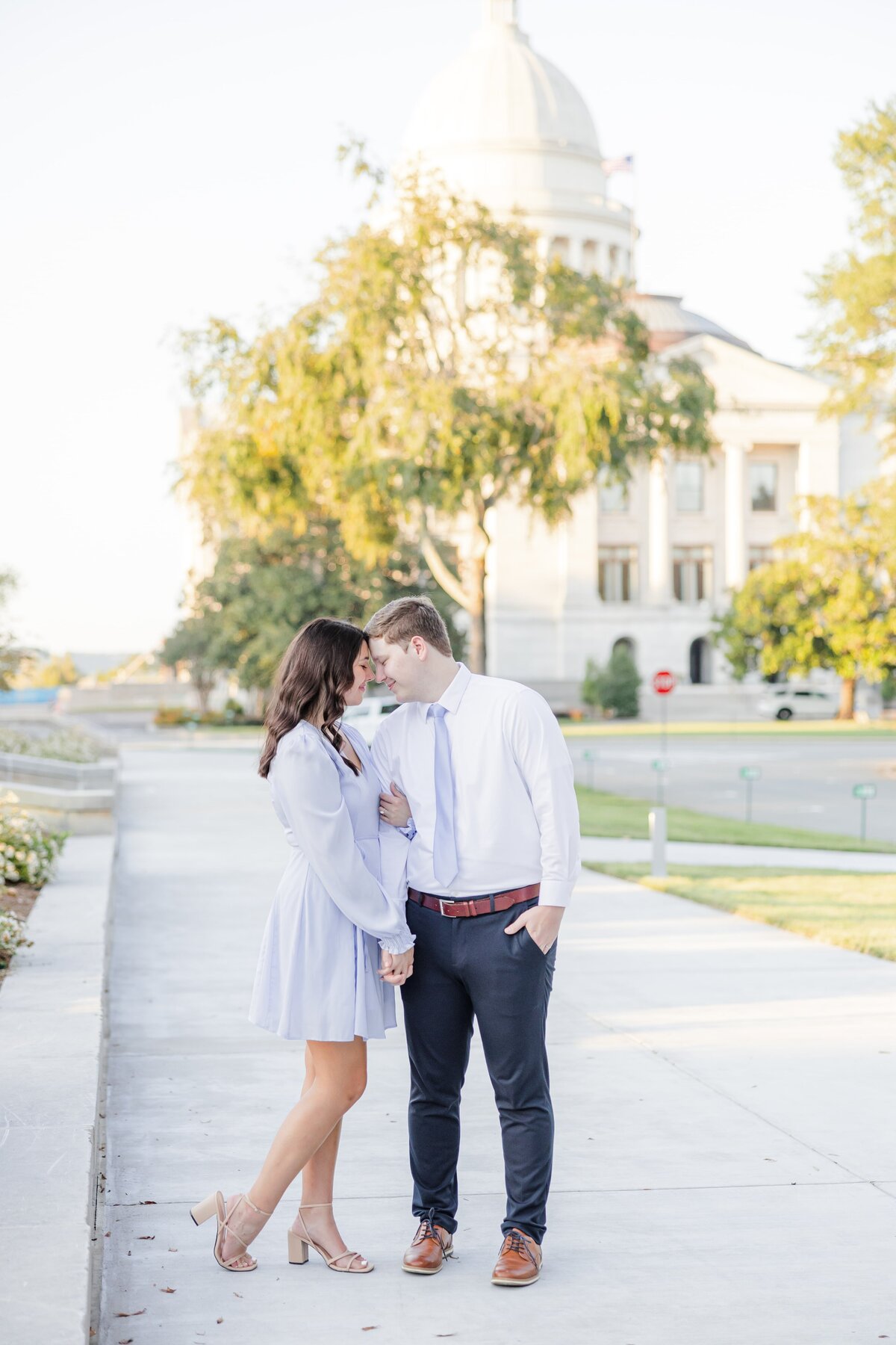 A happy couple snuggles while strolling a park sidewalk