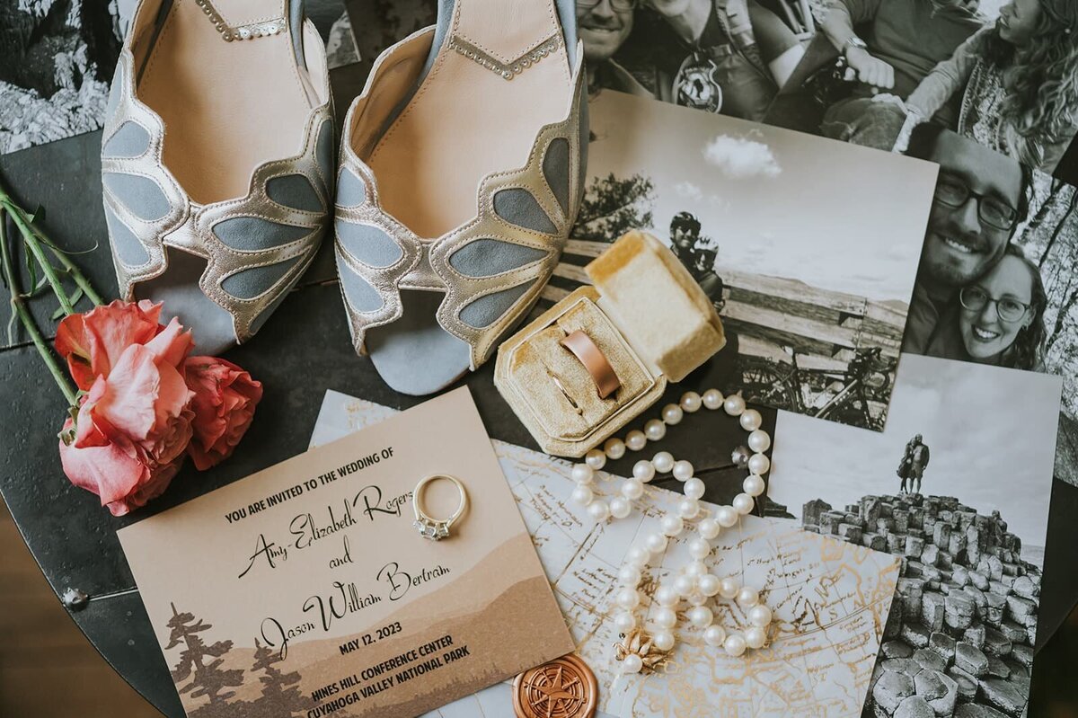 Wedding details of blue high heels, jewelry, and invitations