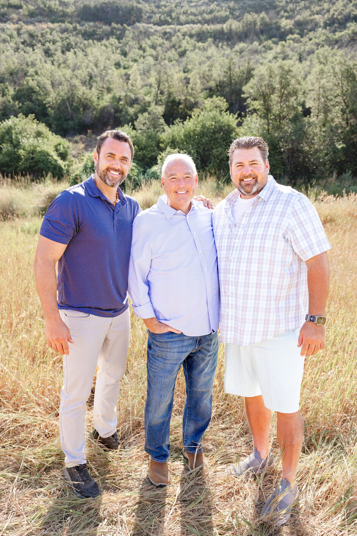 A touching portrait of three generations of men standing together in a scenic outdoor setting, capturing their bond and legacy.
