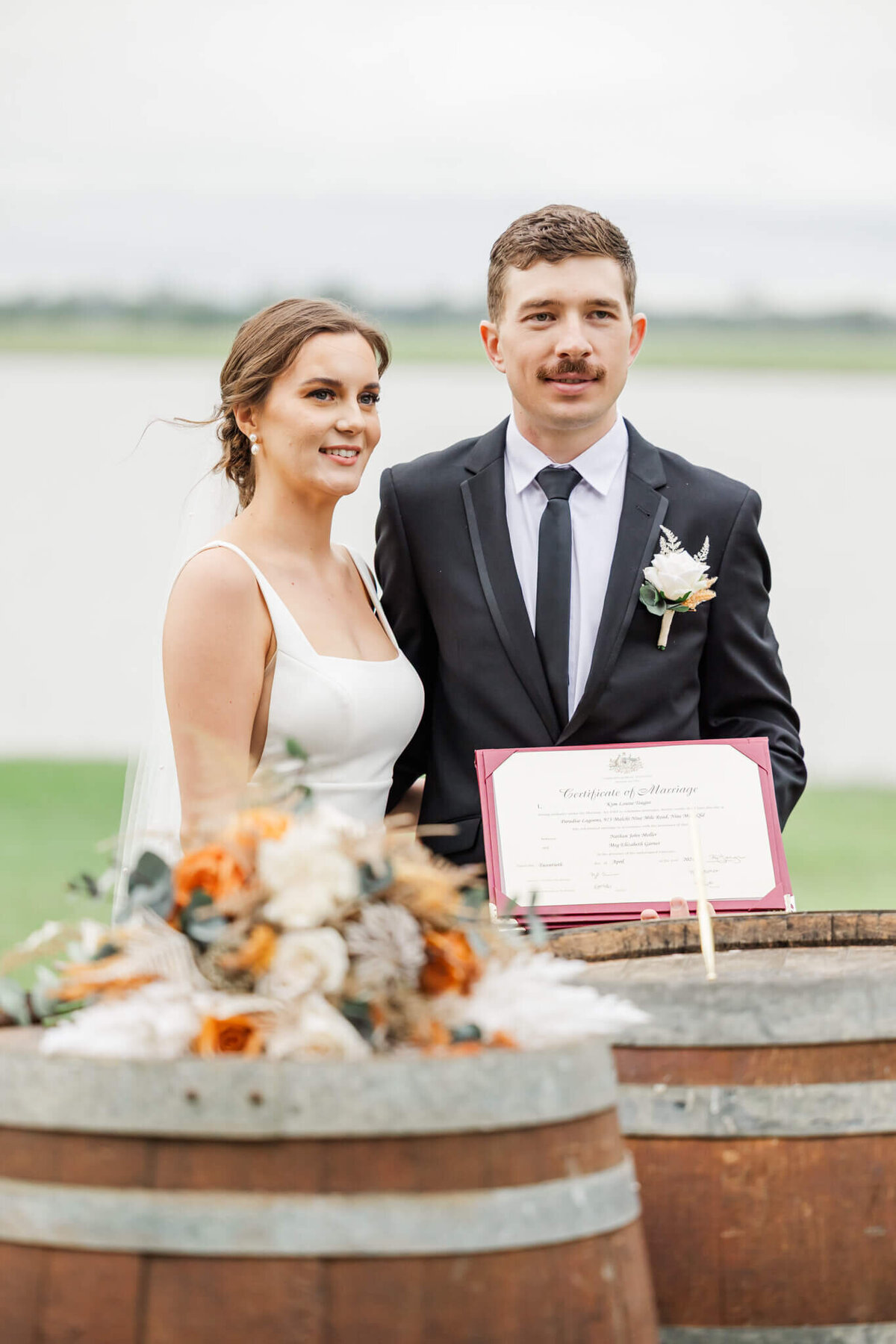 Bride and groom standing together holding thier wedding certificate at Paradise Lagoons wedding venue.