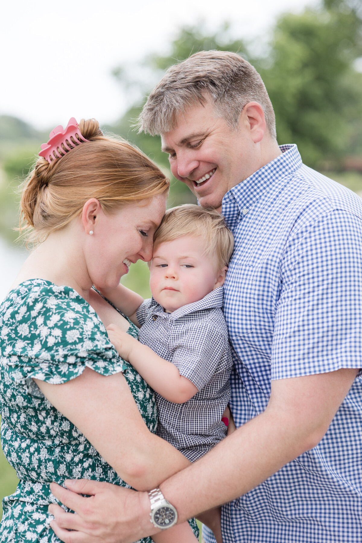 A family holds one another and is smiling at the baby