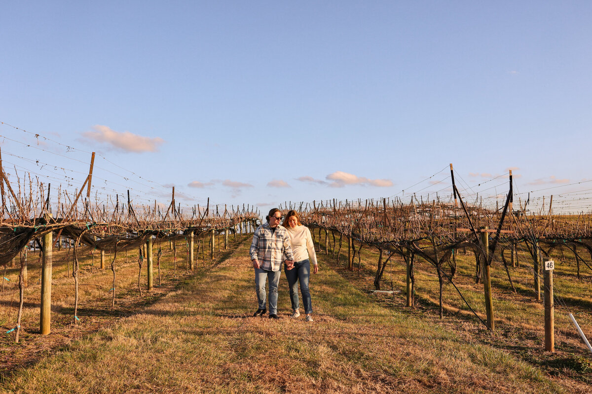 same sex LGBTQ couple holding hands walking in vineyard at Kaya Winery in Dahlonega Georgia by Georgia engagement photographer Amanda Richardson Photography