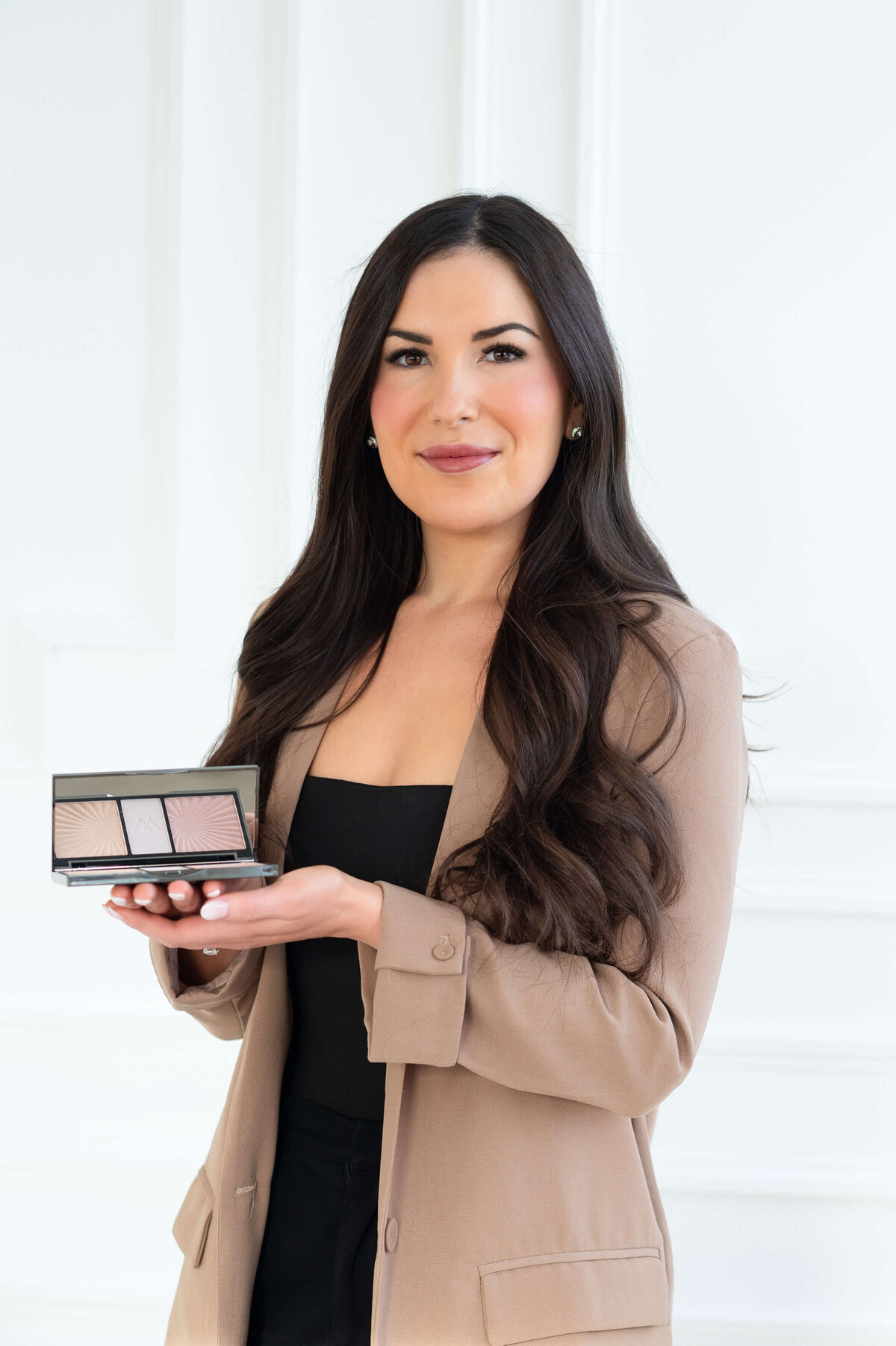 a profile photo of Stephanie Bullock Makeup Artist holding a compact of eyeshadow and smiling at the camera.  Captured in-studio at Skye Studio by Ottawa Branding Photographer JEMMAN Photography COMMERCIAL