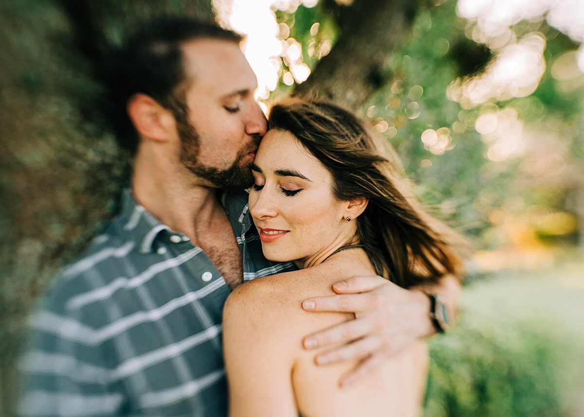Couple hugging during engagement shoot at park