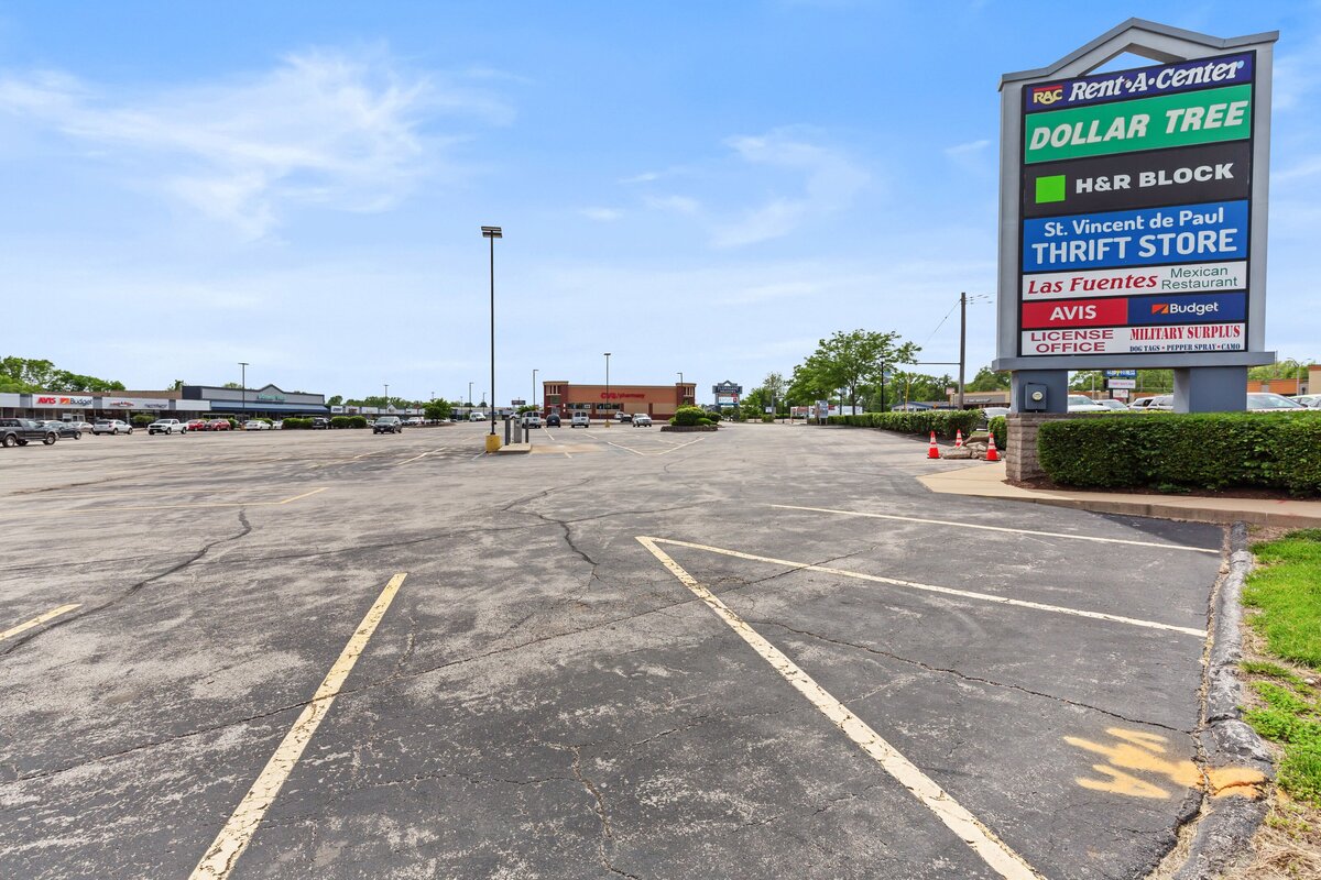 Ground photograph for commercial real estate showing a shopping center sign with the stores in the background.