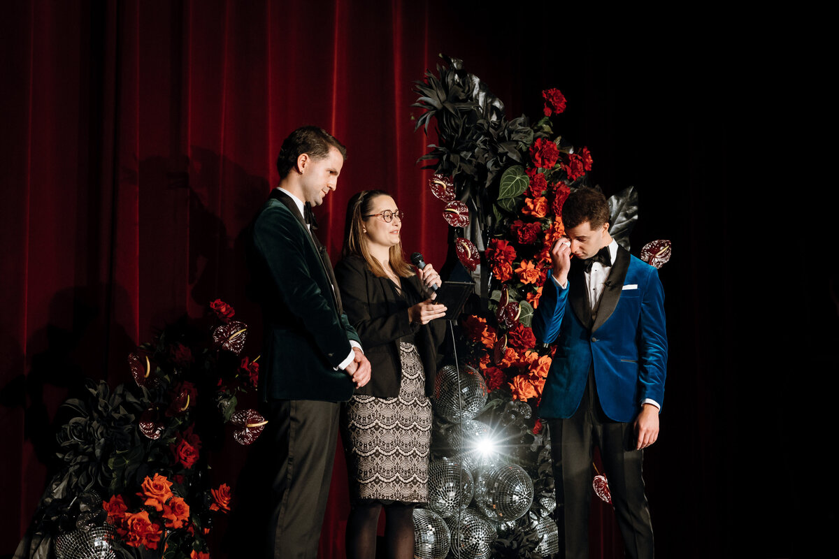 Celebrant and 2 grooms on stage.