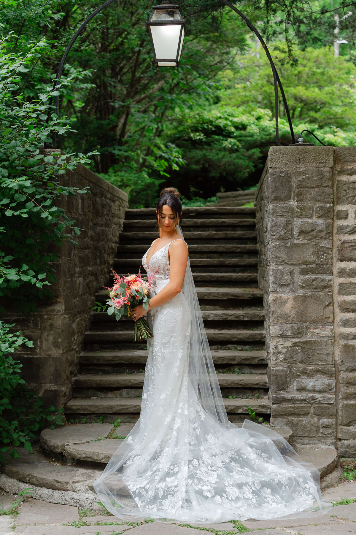 a full length photo of a bride holding her bouquet taken on the stairs of Eaton Hall.  Captured by Ottawa wedding photographer JEMMAN Photography