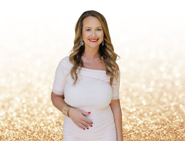 Keri nola in a white dress with a gold sparking background smiling
