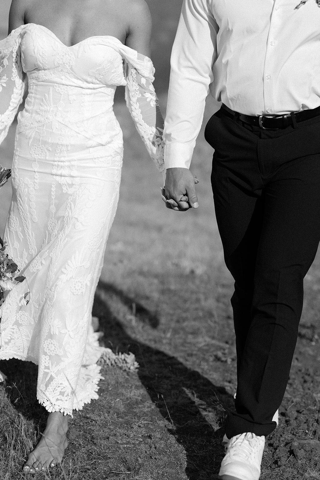 close-up-shot-of-bride-and-groom-holding-hands-while-walking
