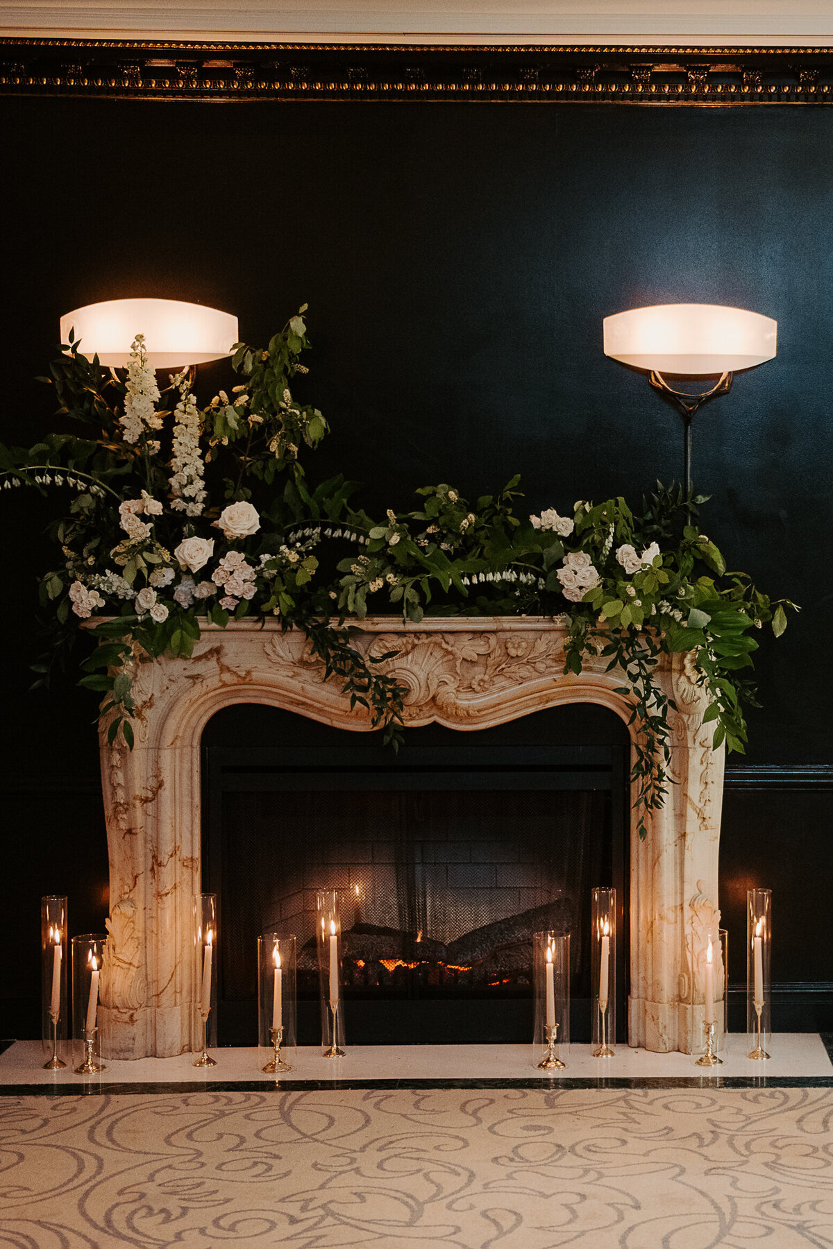Lush greenery and white flowers atop a fireplace at the Ritz hotel for a wedding ceremony.