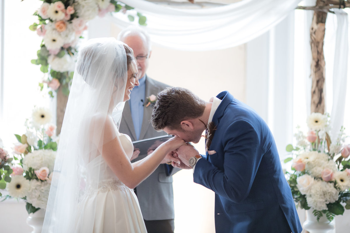 Groom drying tears with bride's hands while they both laugh