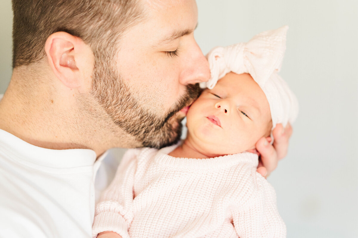 Newborn girl with dad kissing her cheek taken in Douglas, MA by the best newborn photographer in central Massachsuetts